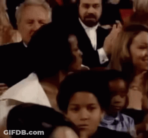 A Crowd Of People Are Sitting In A Stadium Watching A Speech . GIF