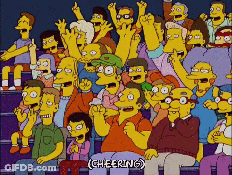 A Crowd Of People Are Sitting In A Stadium With Their Hands In The Air . GIF