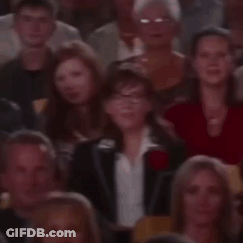 A Crowd Of People Are Sitting In A Theatre Watching A Show . GIF