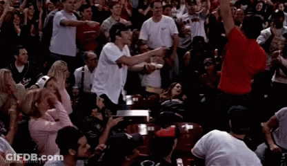 A Crowd Of People Are Watching A Game And One Man In A Red Shirt Is Pointing GIF