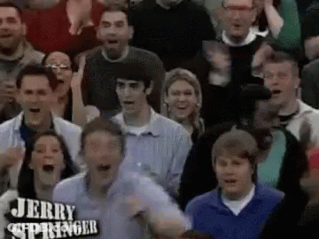 A Crowd Of People Are Watching A Game And One Of Them Is Wearing A Jerry Springer Shirt . GIF