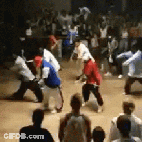 A Crowd Of People Are Watching A Group Of People Dancing In A Room . GIF