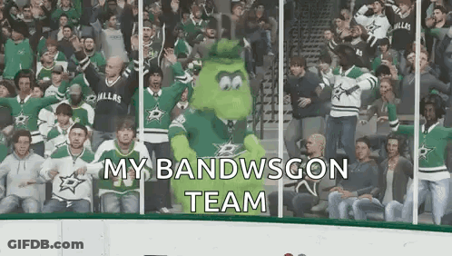 A Crowd Of People Are Watching A Hockey Game And A Mascot Is Standing In The Stands . GIF