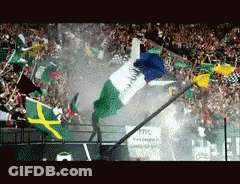 A Crowd Of People Are Watching A Race With Flags Flying In The Air GIF