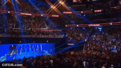 A Crowd Of People Are Watching A Wrestling Match In A Stadium With A Sign That Says ' Wwe ' On It GIF