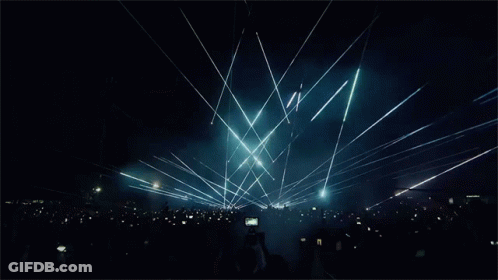 A Crowd Of People At A Concert With Smoke Coming Out Of The Ceiling GIF