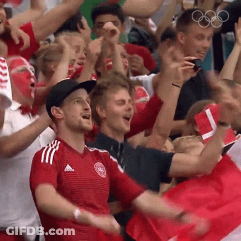 A Crowd Of People Cheering In A Stadium With The Olympic Rings In The Background . GIF