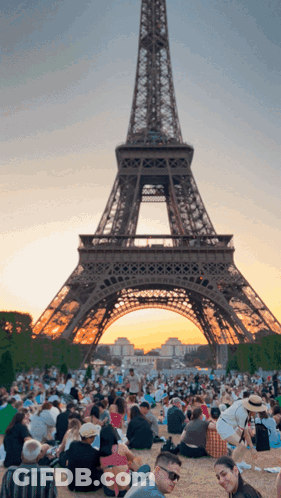 A Crowd Of People Gathered In Front Of The Eiffel Tower GIF