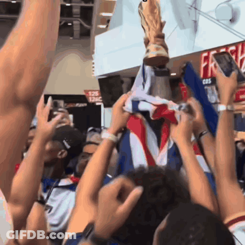 A Crowd Of People Holding A Trophy In Front Of A Sign That Says 126 GIF