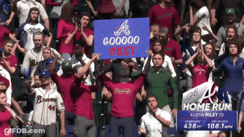 A Crowd Of People Holding Up A Sign That Says Gooooo Riley GIF