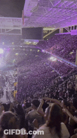 A Crowd Of People In A Stadium With Purple Lights GIF