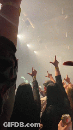 A Crowd Of People Raising Their Hands In The Air At A Concert GIF