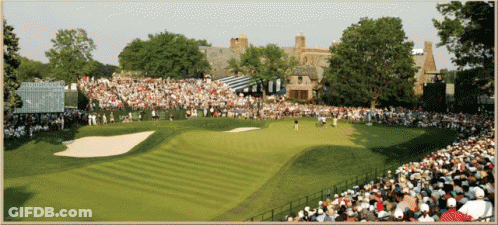 A Crowd Of People Watching A Golf Course With A Scoreboard In The Background GIF
