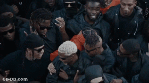 A Crowd Of People With One Wearing Sunglasses And A Necklace That Says Armour GIF