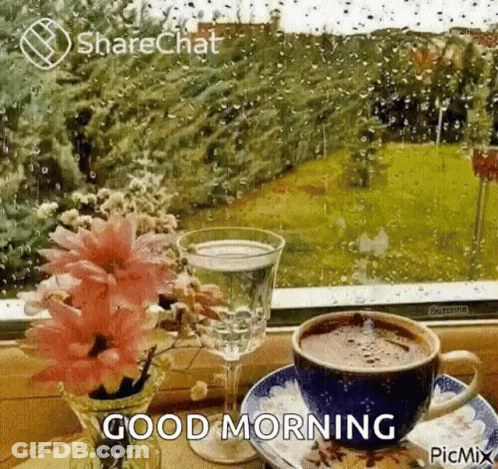 A Cup Of Coffee And A Glass Of Water Are On A Table In Front Of A Window With Rain Drops . GIF