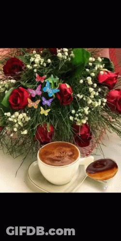 A Cup Of Coffee Is On A Saucer Next To A Bouquet Of Flowers GIF
