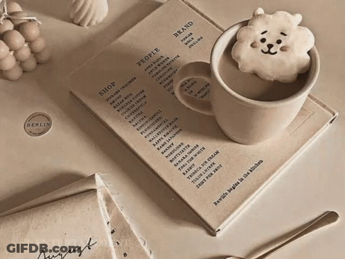 A Cup Of Coffee Sits On Top Of A Book That Says People GIF