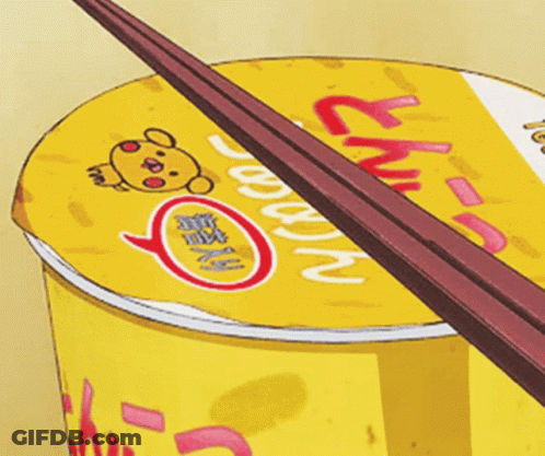 A Cup Of Ramen With Chopsticks Sticking Out Of The Top GIF