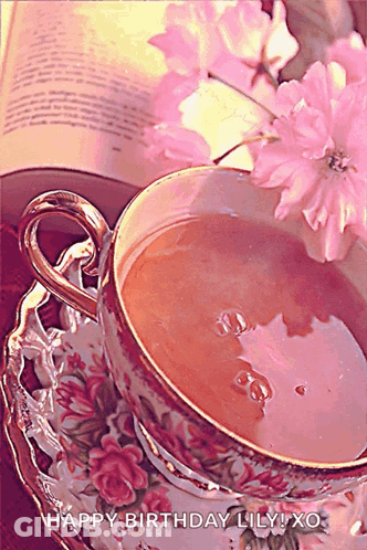 A Cup Of Tea Sits On A Saucer Next To A Book And Pink Flowers With The Words Happy Birthday Lily Xo GIF