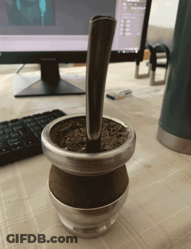 A Cup Of Yerba Mate Sits On A Table Next To A Computer Monitor GIF