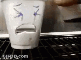 A Cup With A Face Drawn On It Is Sitting On A Shelf GIF
