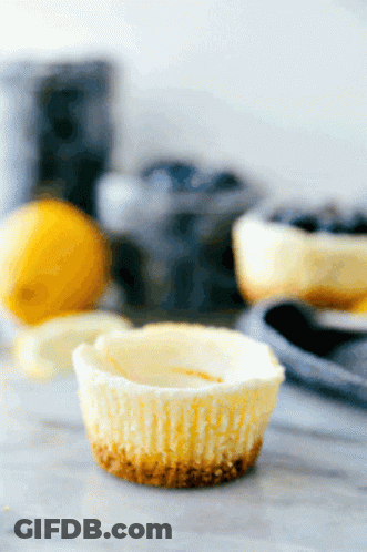 A Cupcake Is Sitting On A Table With Lemons And Blueberries In The Background GIF