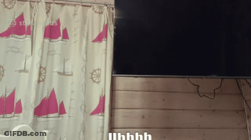A Curtain With Sailboats And Steering Wheels Hangs Next To A Flat Screen Tv GIF