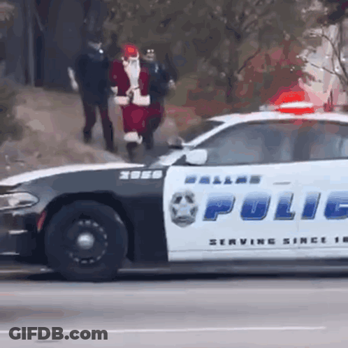A Dallas Police Car Is Driving Down The Street With Santa Claus On The Back GIF