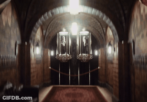 A Dark Hallway With A Red Carpet And Two Displays GIF