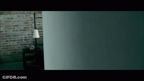 A Dark Room With A Brick Wall And A Lamp On A Table GIF