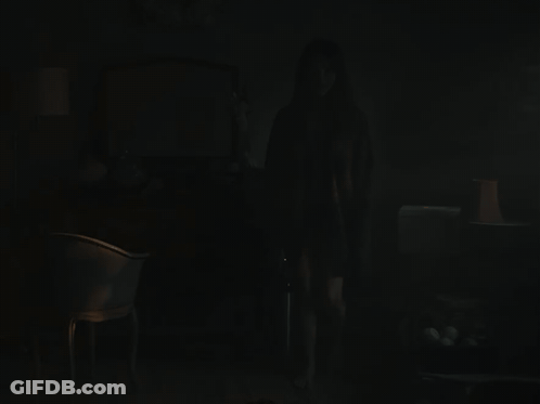 A Dark Room With A Chair And A Lamp On GIF