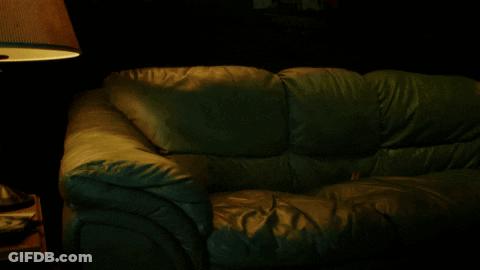 A Dark Room With A Couch And A Lamp GIF