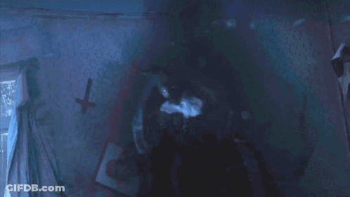 A Dark Room With A Cross On The Wall And A Picture On The Wall GIF