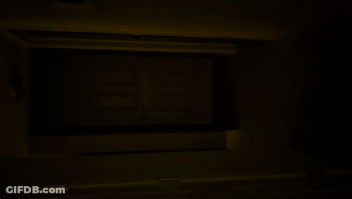 A Dark Room With A Few Lights On And A Person Walking Down The Stairs GIF