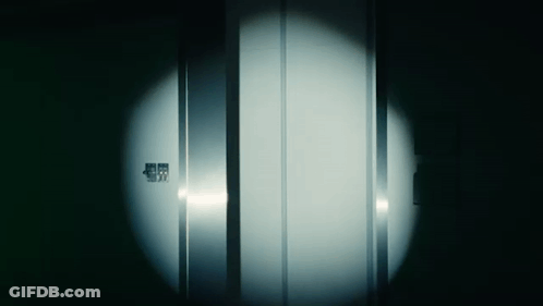 A Dark Room With A Light Shining On A Door That Says ' Emergency Exit ' On It GIF