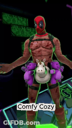 A Deadpool Holding A Stuffed Unicorn And Teddy Bears With The Words Comfy Cozy Below Him GIF
