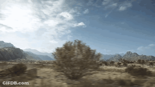A Desert Landscape With Mountains In The Background And Trees In The Foreground GIF
