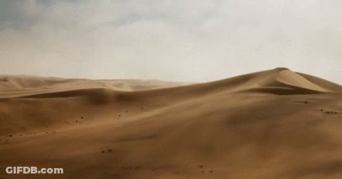 A Desert Landscape With Sand Dunes And Mountains In The Distance GIF