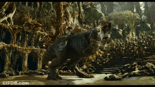 A Dinosaur Is Walking Through A Cave With A Lot Of Trees GIF