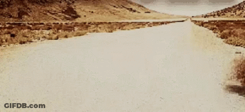A Dirt Road With Mountains In The Background GIF
