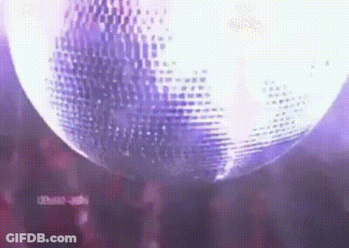 A Disco Ball Is Spinning In A Dark Room With Purple Lights . GIF