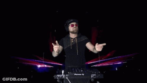 A Dj Wearing Headphones And Sunglasses Stands In Front Of A Pioneer Dj Controller GIF
