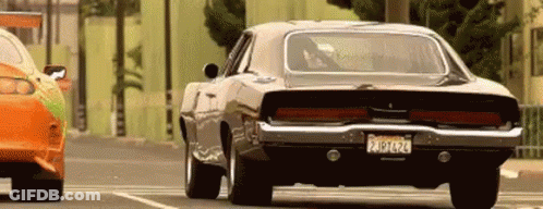 A Dodge Charger Is Driving Down A Street Next To Another Car With A License Plate That Says California GIF