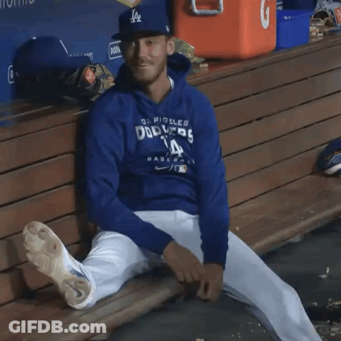 A Dodgers Player Sits On A Bench With His Legs Crossed GIF