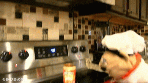 A Dog Wearing A Chef 'S Hat Is Cooking On A Stove Top GIF