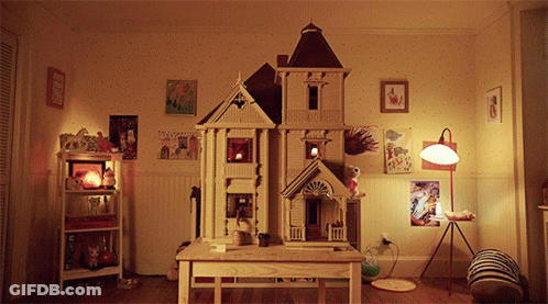 A Doll House Sits On A Wooden Table In A Bedroom GIF