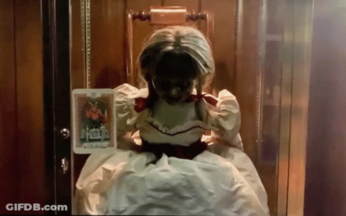 A Doll In A White Dress Is Sitting In A Chair Holding A Book GIF