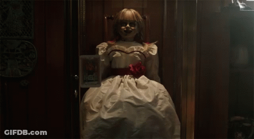 A Doll In A White Dress With A Red Rose Around Her Waist Is Standing In A Doorway GIF