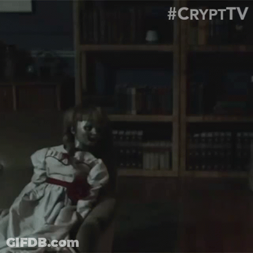 A Doll Is Sitting In A Dark Room With A Bookshelf In The Background . GIF