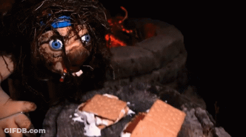 A Doll With A Blue Headband Is Eating S'mores GIF